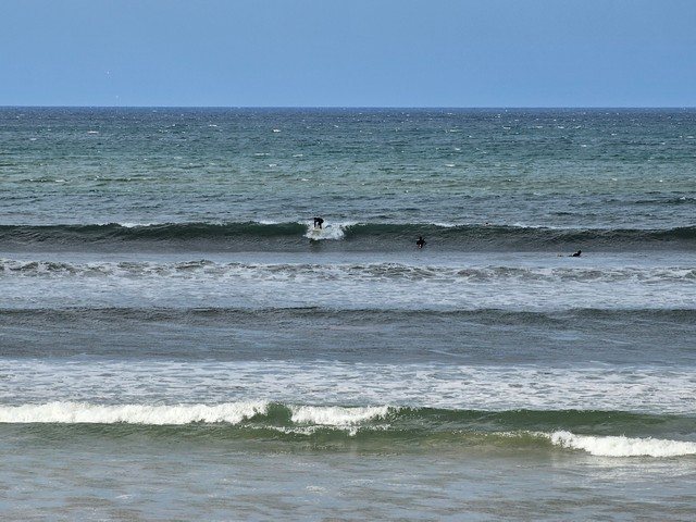Surfer getting to their feet on a head high wave in front of the shop